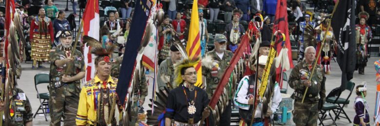 8 Indigenous people gather together and present flags and eagle staphs to be honored at a Pow Wow Grand Entry Ceremony in Minnesota.